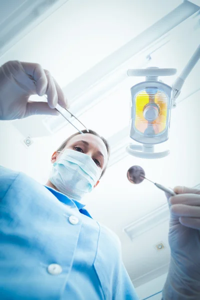 Female dentist in surgical mask holding dental tools — Stock Photo, Image