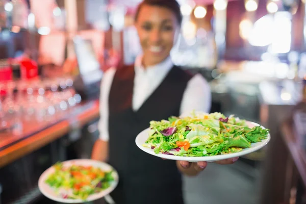 Bonito barmaid segurando pratos de saladas — Fotografia de Stock