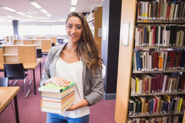 Pretty student smiling at camera in library — Stock Photo, Image