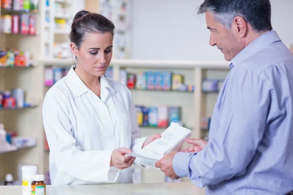 Customer handing a prescription to a trainee — Stock Photo, Image