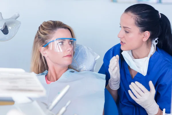 Dentist talking with patient in chair — Stock Photo, Image