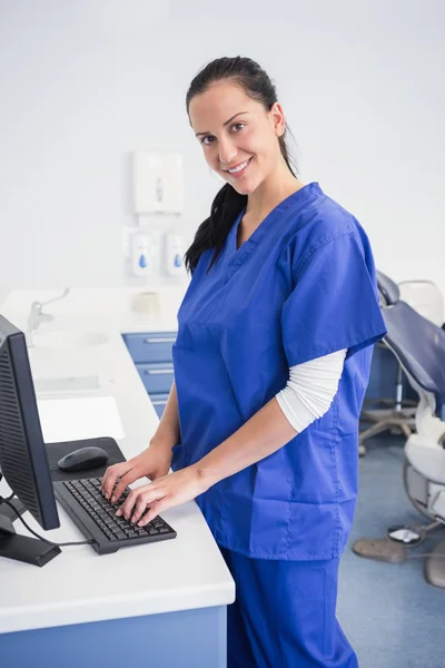 Dentiste souriant tapant sur le clavier — Photo