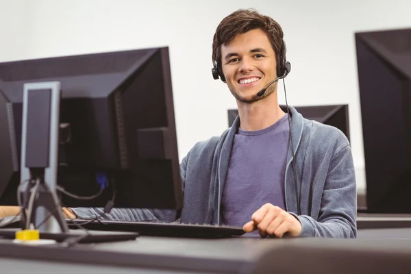 Estudiante sentado en la sala de computadoras con auriculares —  Fotos de Stock