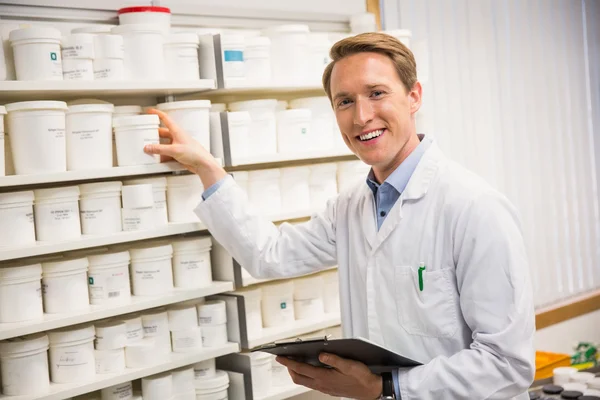 Guapo farmacéutico tomando medicamentos de la estantería —  Fotos de Stock