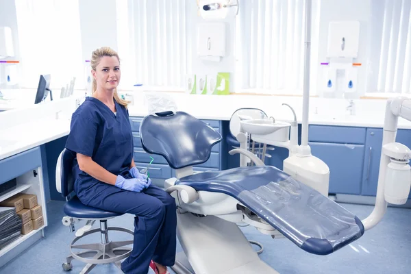 Dentista sorridente alla macchina fotografica accanto alla sedia — Foto Stock