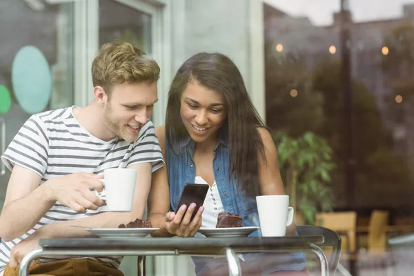 Amigos sonrientes con pastel de chocolate usando smartphone — Foto de Stock