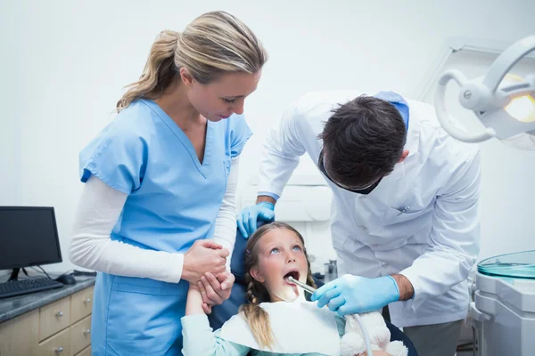 Dentista con asistente examinando los dientes de las niñas — Foto de Stock