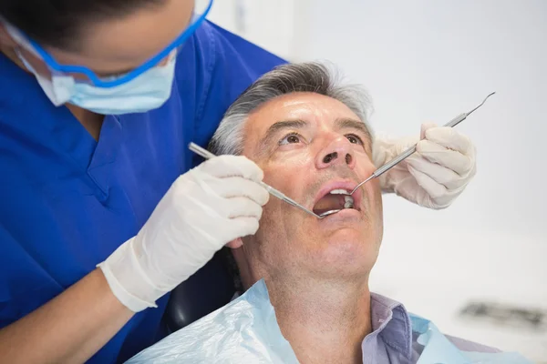 Dentista examinando a un paciente con herramientas — Foto de Stock