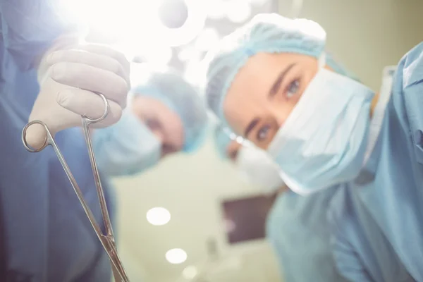 Young surgeons holding clamp — Stock Photo, Image