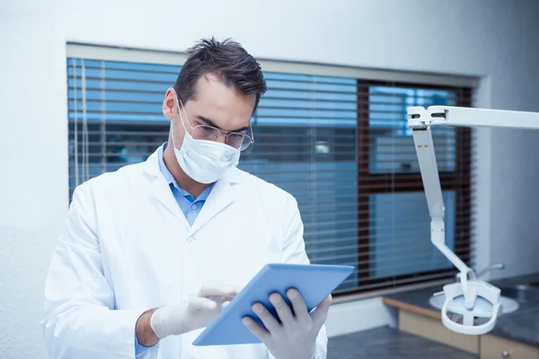 Dentista en máscara quirúrgica usando tableta digital — Foto de Stock