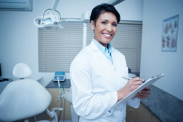 Sorridente dentista femminile che tiene appunti — Foto Stock