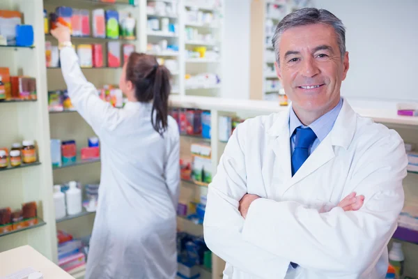 Farmacista guardando la fotocamera con lo studente dietro di lui — Foto Stock