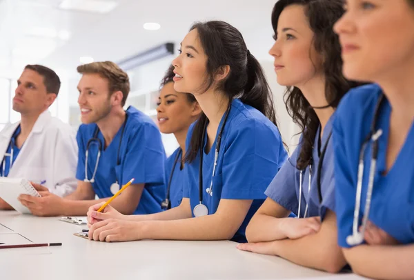 Studenti di medicina che ascoltano seduti alla scrivania — Foto Stock