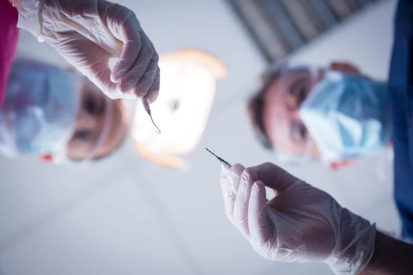 Стоматолог и ассистент наклоняются над пациентом с помощью инструментов — стоковое фото