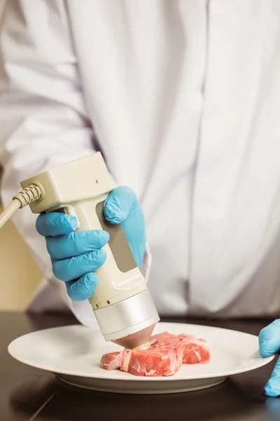 Food scientist using device on meat — Stock Photo, Image