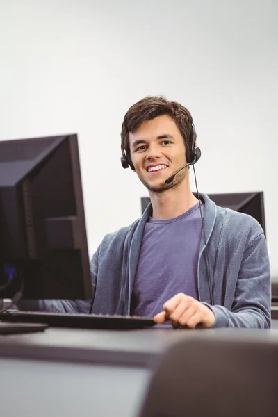 Estudiante sentado en la sala de computadoras con auriculares —  Fotos de Stock