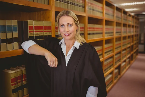 Uśmiechający się prawnik opierając się na półce — Zdjęcie stockowe