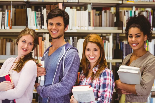 Estudiantes en una línea sonriendo a la cámara sosteniendo libros —  Fotos de Stock