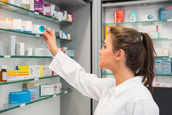 Pharmacien junior prenant des médicaments sur étagère — Photo