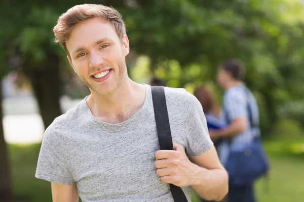 Przystojny student uśmiecha się do kamery na zewnątrz na kampusie — Zdjęcie stockowe