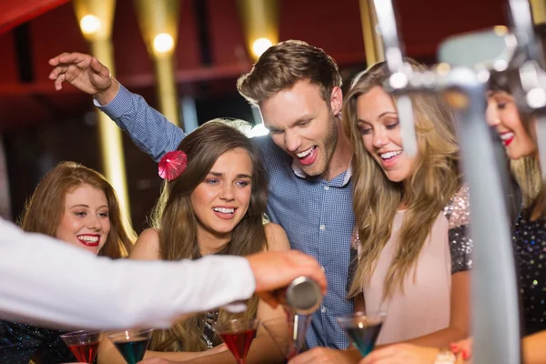 Пьяные друзья смотрят, как бармен наливает коктейль — стоковое фото