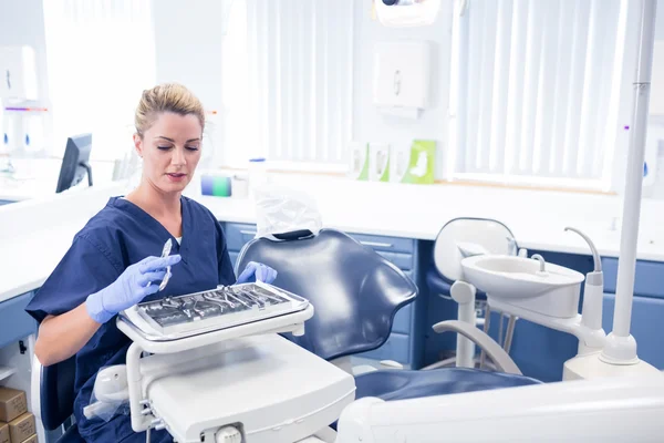 Улыбающийся стоматолог сидит с подносом с инструментами — стоковое фото