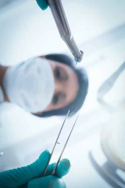 Female dentist in surgical mask holding dental tools — Stock Photo, Image