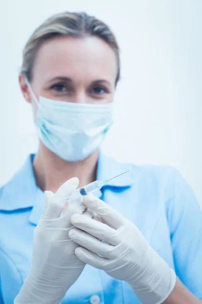 Dentista femenina en máscara quirúrgica que sostiene la inyección — Foto de Stock