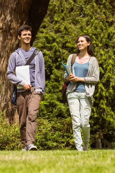 Friends students walking with shoulder bag and holding notepad — Stock Photo, Image