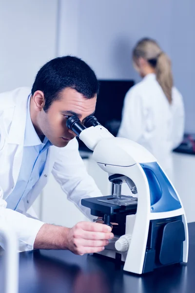 Estudante de ciência olhando através do microscópio no laboratório — Fotografia de Stock