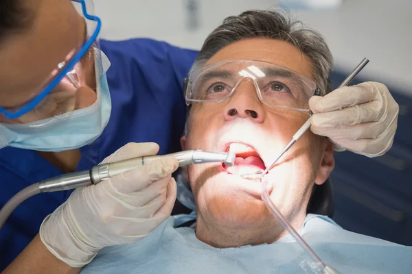 Dentysta bada pacjenta z narzędzia i światło — Zdjęcie stockowe