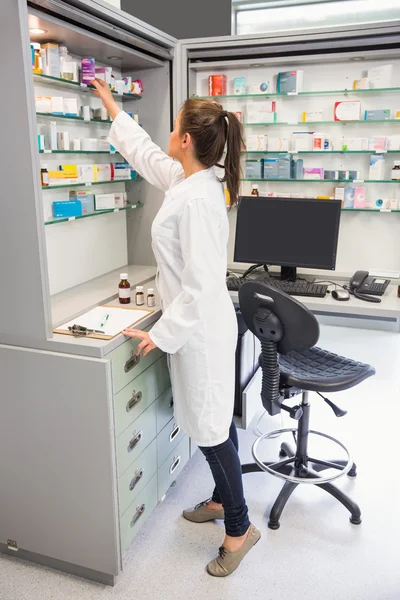 Junior pharmacist taking medicine from shelf — Stock Photo, Image