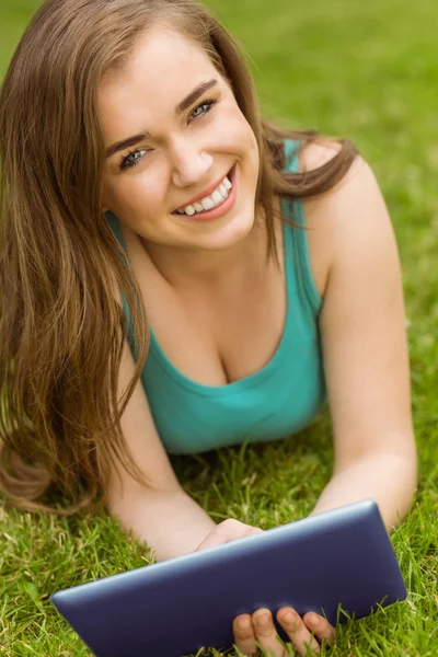 Sorridente studente universitario sdraiato e utilizzando tablet pc — Foto Stock