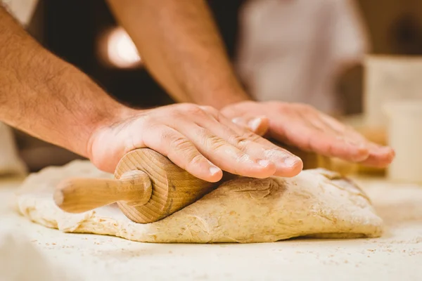 Пекарь катит тесто на прилавке — стоковое фото