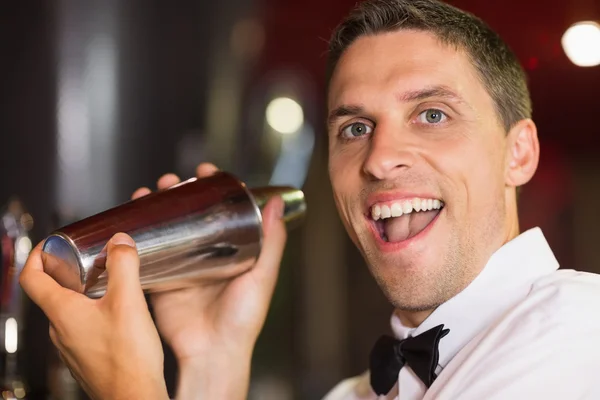 Симпатичный бармен, улыбающийся в камеру и делающий коктейль — стоковое фото