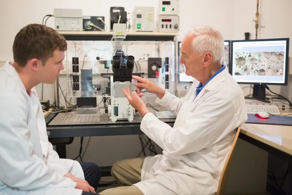 Biochemiker mit großem Mikroskop und Computer — Stockfoto