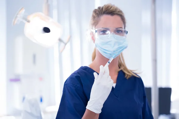 Dentista con máscara y guante sosteniendo una inyección — Foto de Stock