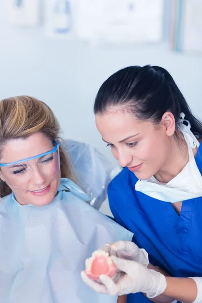 Dentist showing patient model of teeth — Stock Photo, Image