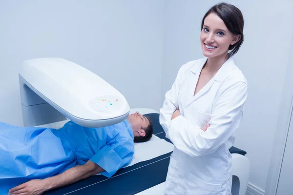 Médico sonriente con un paciente bajo máquina de rayos X —  Fotos de Stock