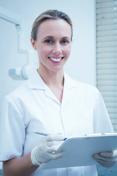 Χαμογελαστά γυναικεία οδοντίατρος κρατώντας πρόχειρο — Φωτογραφία Αρχείου