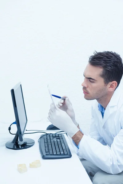 Dentist looking at x-ray by computer — Stock Photo, Image