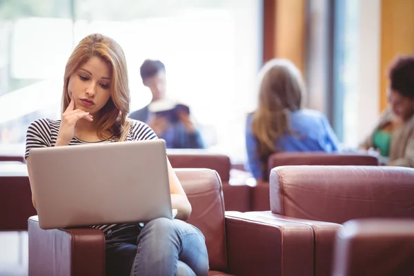 Studente concentrato seduto sul divano utilizzando il computer portatile — Foto Stock