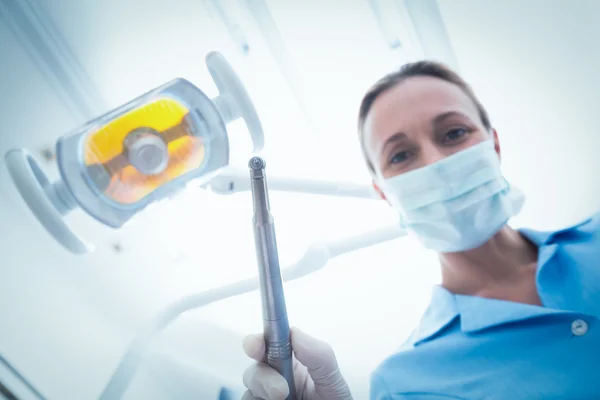 Dentista feminina em máscara cirúrgica segurando ferramenta dentária — Fotografia de Stock