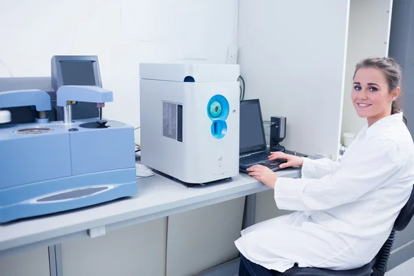 Smiling young biochemist using laptop — Stock Photo, Image