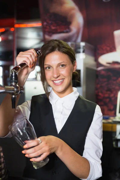 Happy barmaid pulling a pint of beer — Stock Photo, Image