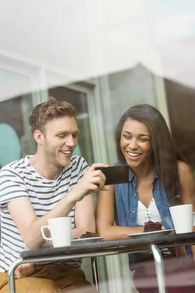 Amis souriants avec gâteau au chocolat en utilisant smartphone — Photo