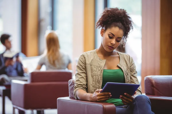 Konzentrierte Studentin sitzt mit Tablet-PC auf Sofa — Stockfoto