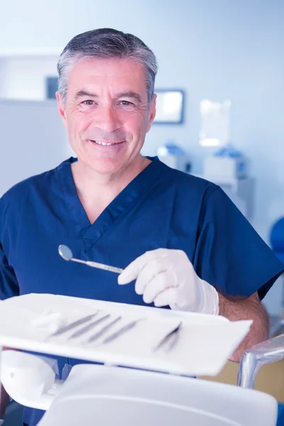 Dentist in blue scrubs holding tools — Stock Photo, Image