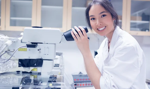 Joli scientifique souriant à la caméra à l'aide du microscope — Photo