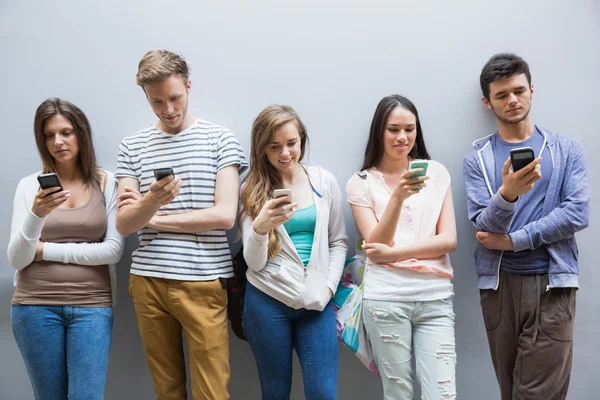 Estudantes usando seus smartphones em uma fileira — Fotografia de Stock